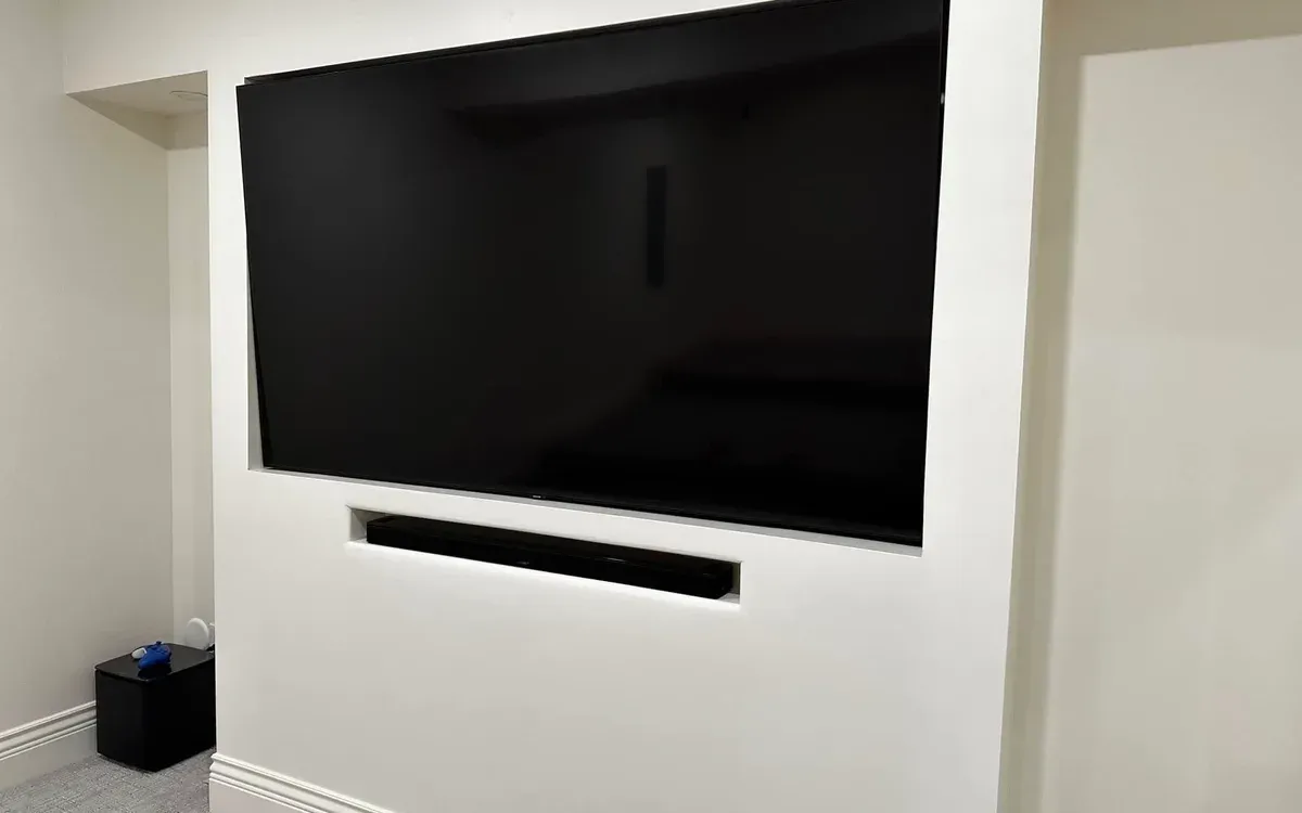 Large TV and soundbar flush-mounted in custom built-in media wall