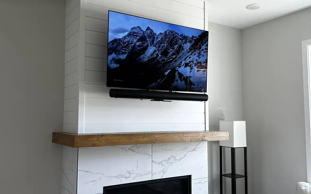 TV and soundbar mounted above modern fireplace with shiplap accent wall